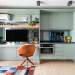 Caixa de marcenaria verde abriga cozinha, bancada e tv em estúdio de 34 m²